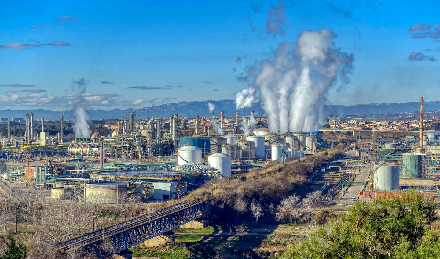 Industrial refinery complex with pipes and steaming chimneys.