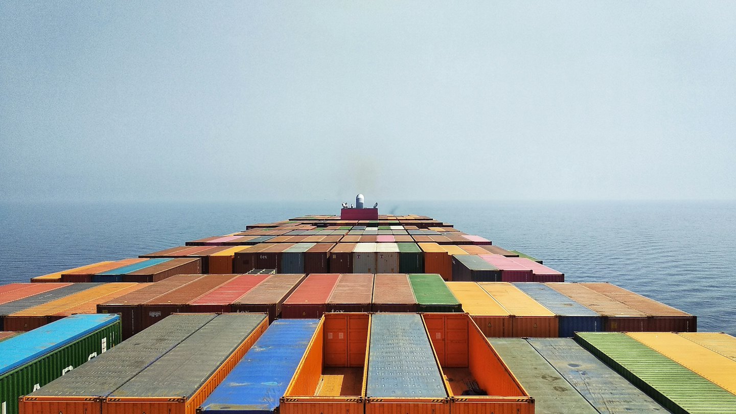 Cargo ship loaded with colorful containers sails on a vast blue ocean.