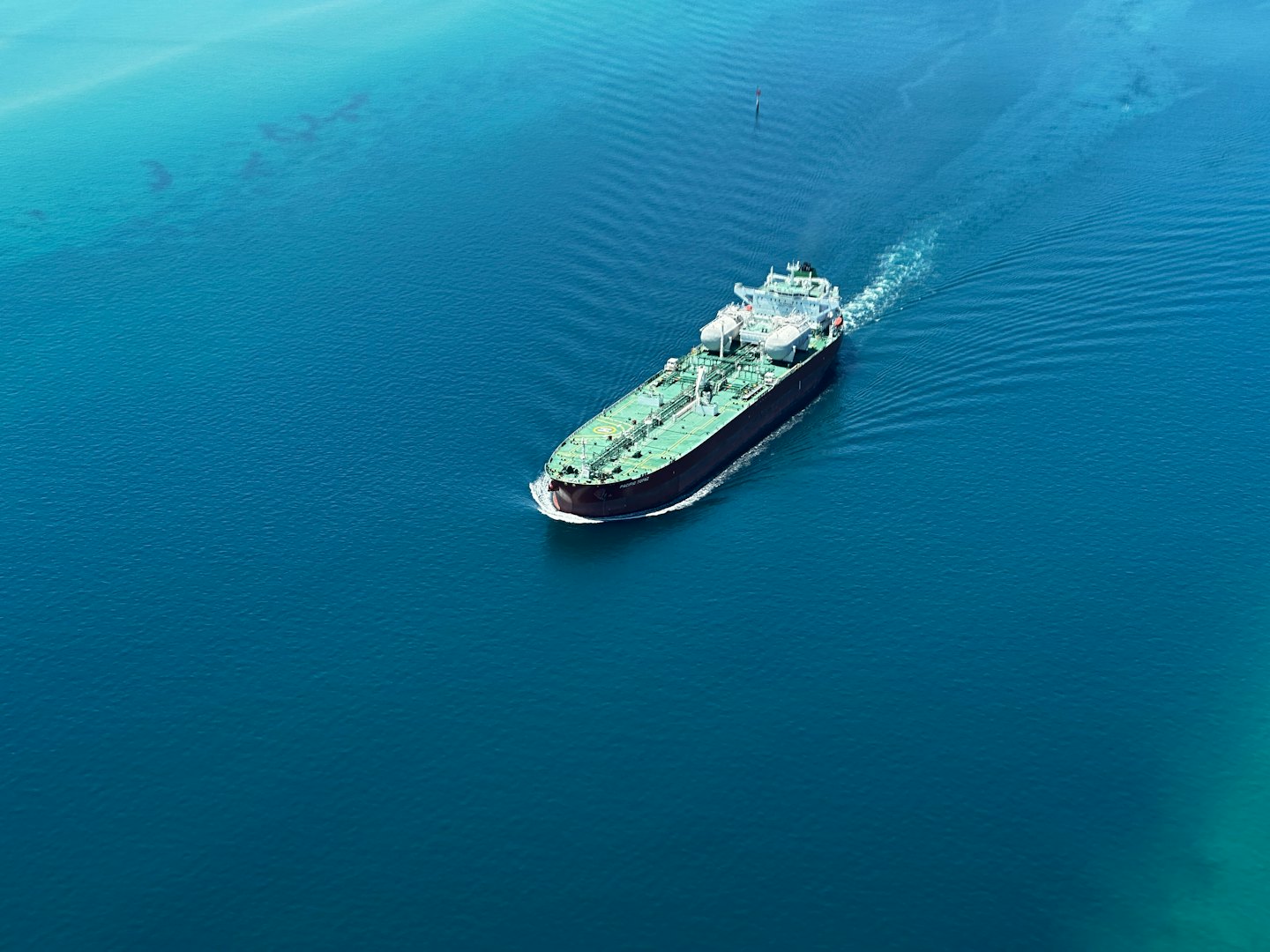 Cargo ship sailing across deep blue ocean water.