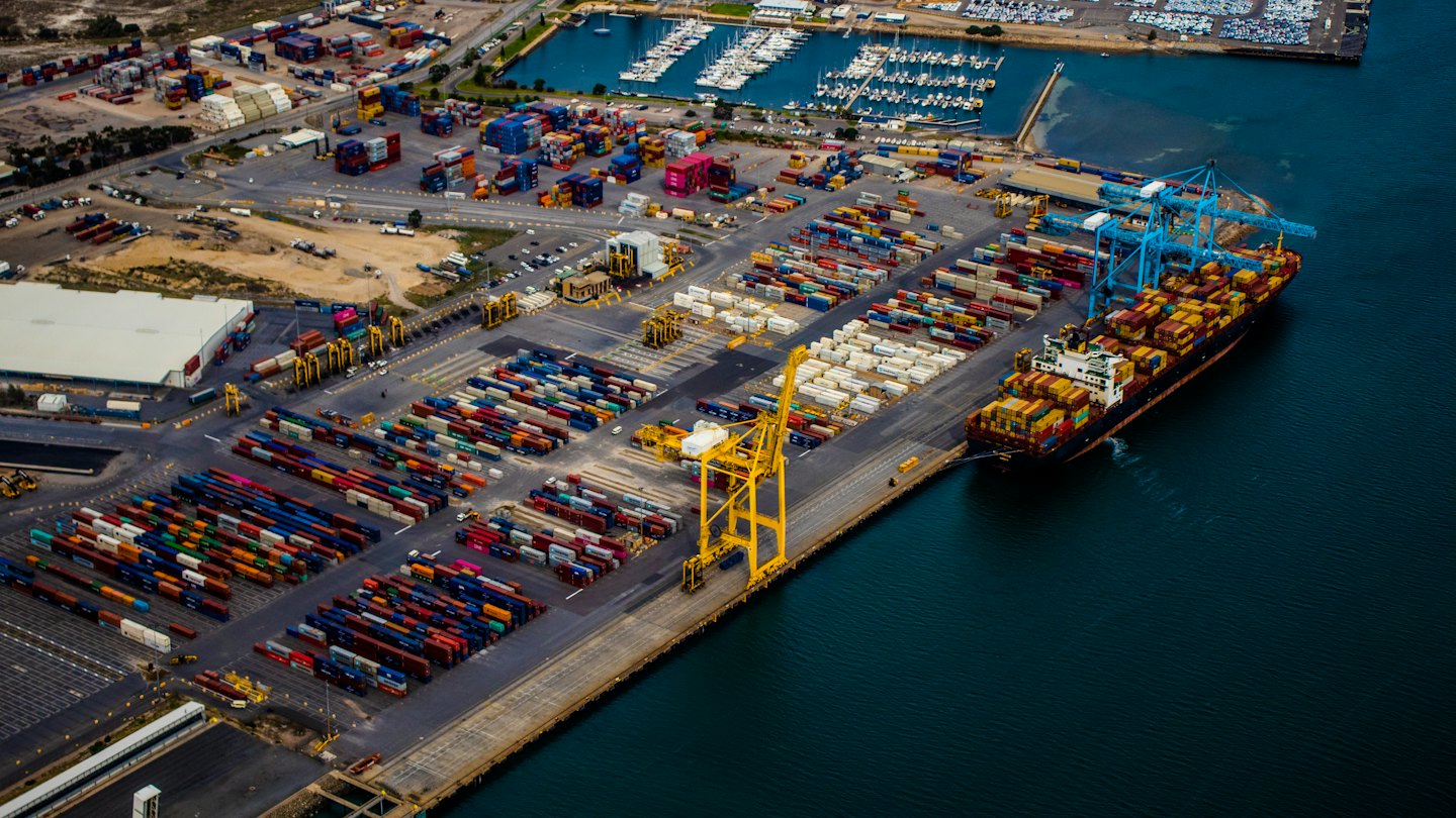 Cargo ship being loaded by gantry cranes at a busy port.
